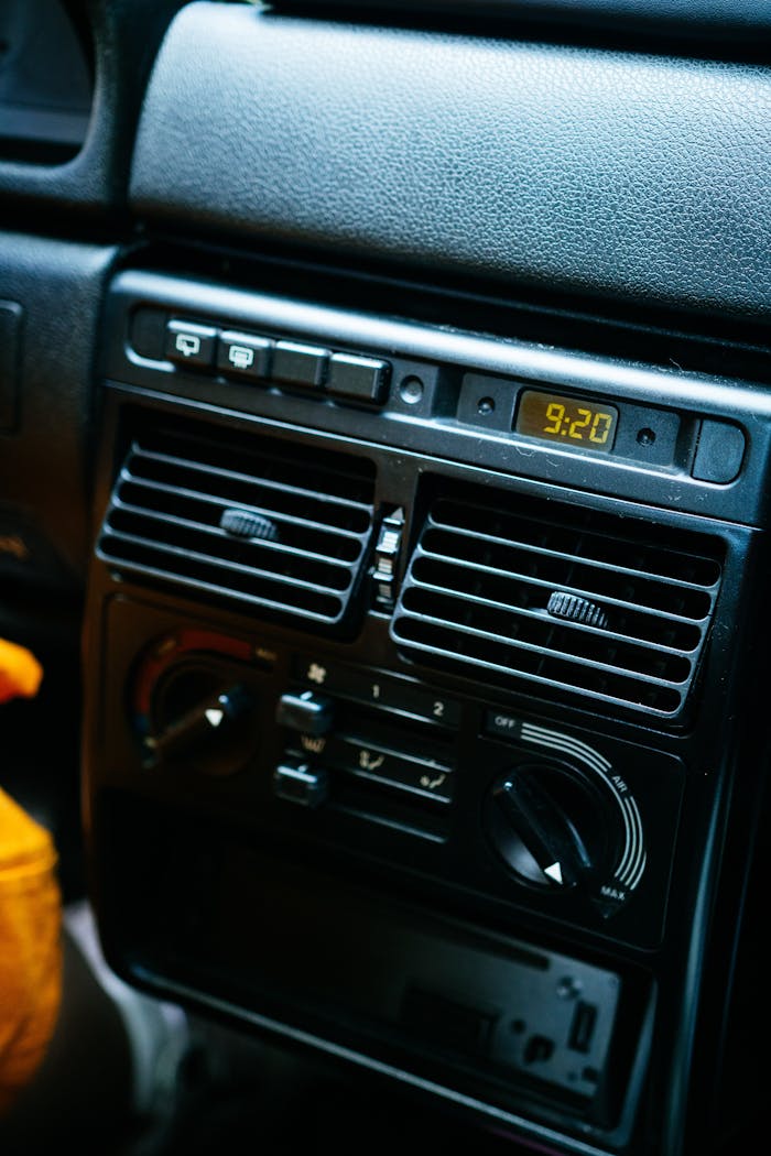 Detailed view of a car dashboard with electronic controls and digital clock. mobile air conditioning service